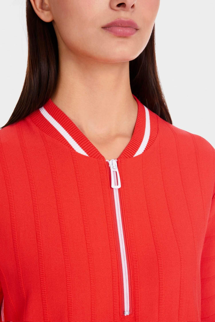 Détail d'une robe en tricot rouge avec col zippé et rayures blanches, vue de près sur le cou.