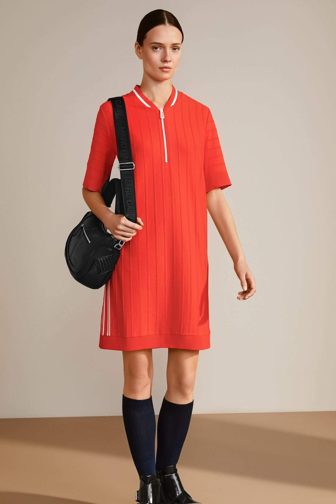 Robe en tricot rouge à manches courtes avec col et sac noir, modèle élégant et moderne.