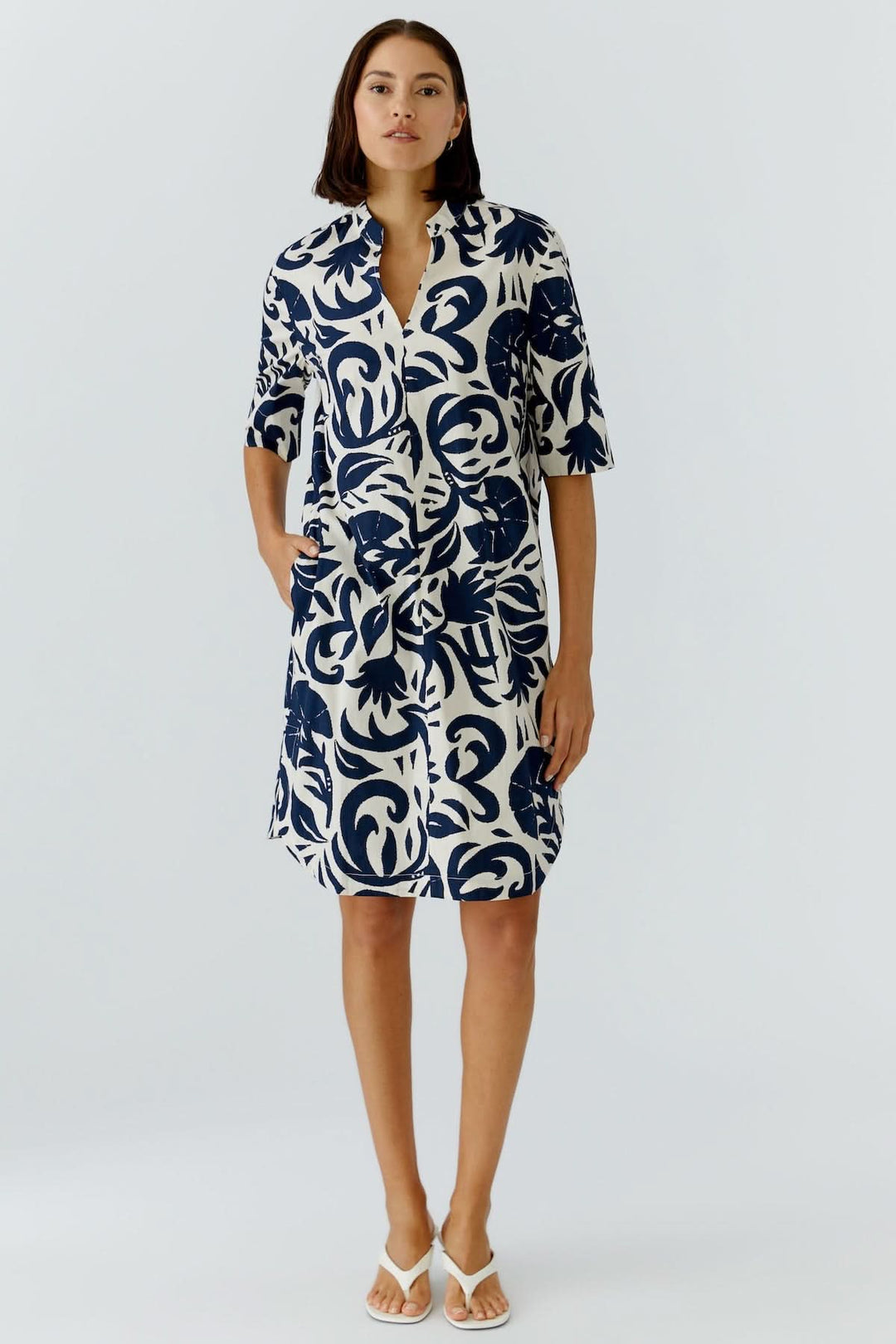 Robe fluide à imprimé graphique, coupe droite, élégante, portée par une femme sur fond blanc.