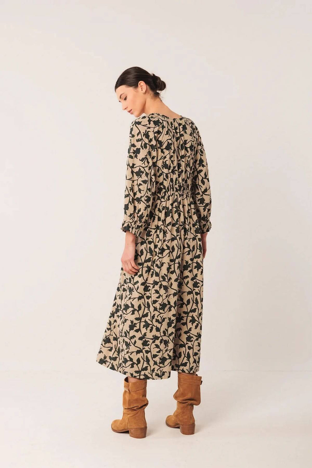 Robe longue fluide au imprimé botanique, décolleté en V, portée avec des bottes en cuir, look bohème.