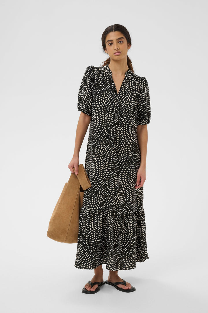 Femme portant une robe longue imprimée à taille ceinturée avec manches bouffantes, style élégant et fluide pour quotidien ou occasions spéciales.