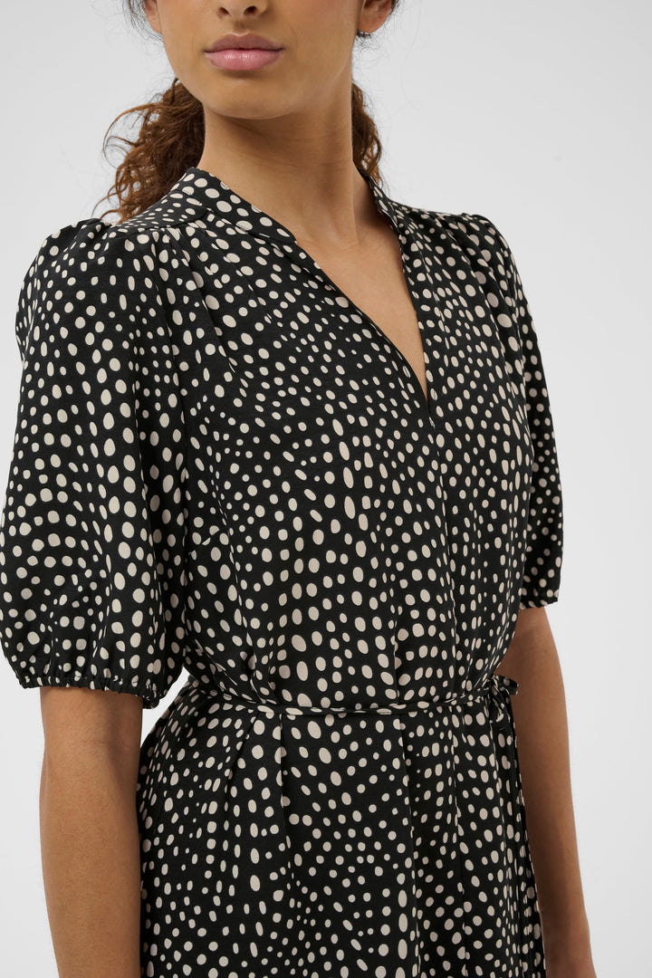 Femme portant robe longue imprimée à taille ceinturée, manches courtes bouffantes, élégante et confortable pour toutes occasions.