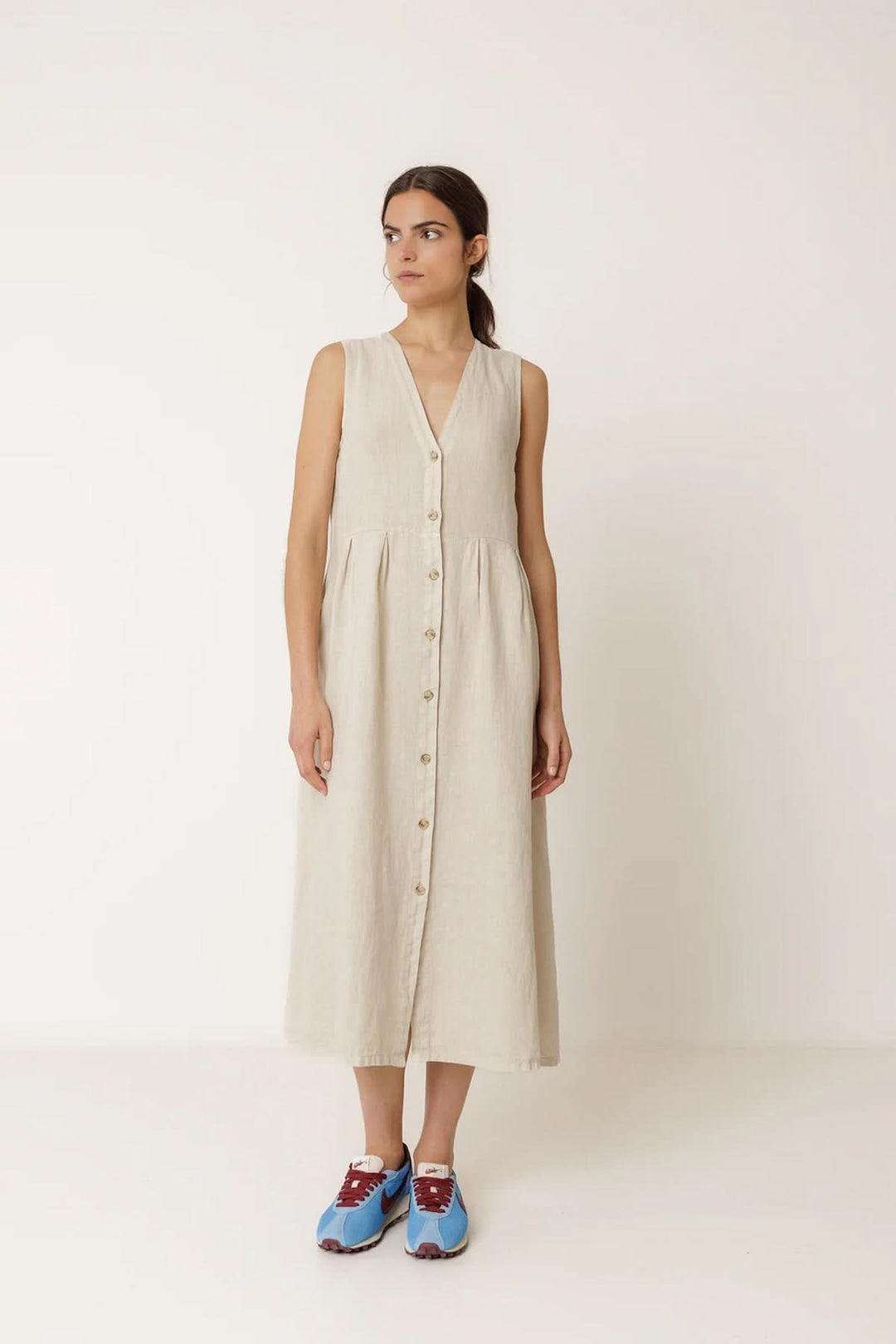Robe longue réversible sans manches en lin beige avec encolure en V, portée par une femme, offrant deux styles élégants.