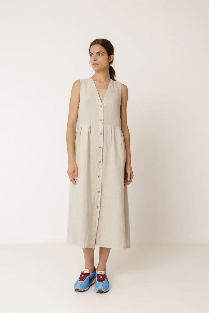 Robe longue réversible sans manches en lin beige avec encolure en V, portée par une femme, offrant deux styles élégants.