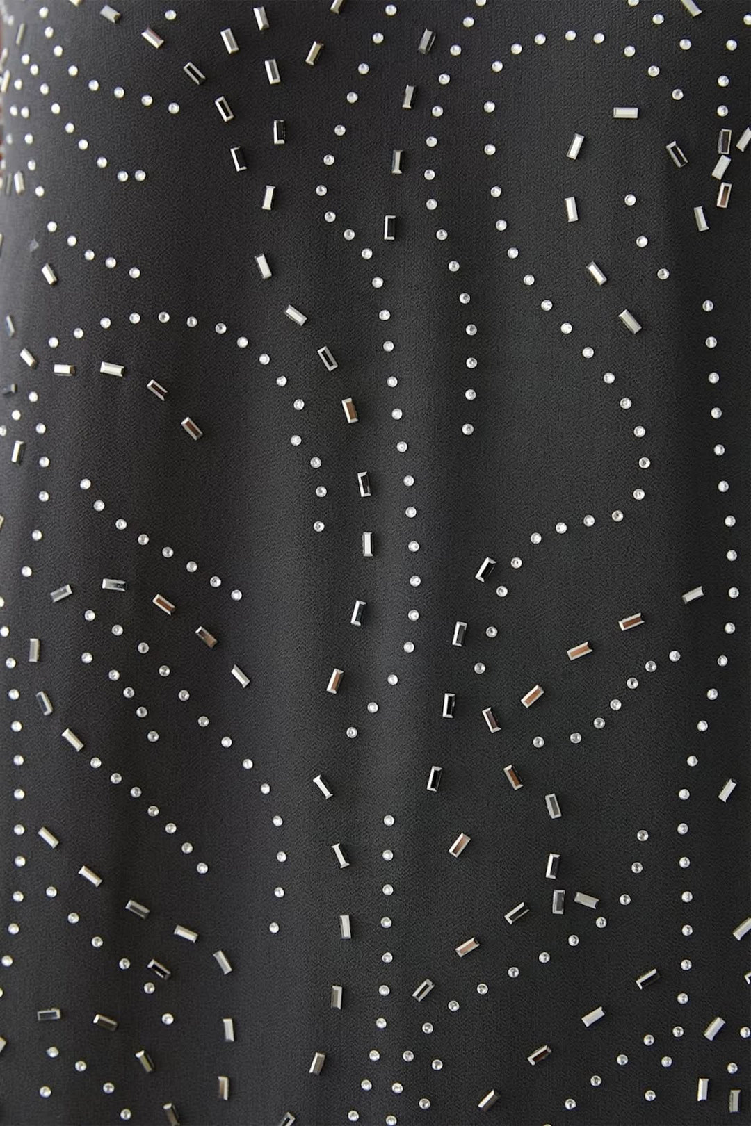 Gros plan sur l'imprimé à motifs discrets en pointillés sur une robe longue élégante et fluide en tissu noir.