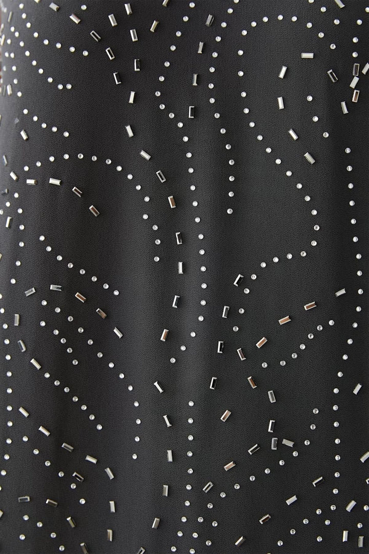 Gros plan sur l'imprimé à motifs discrets en pointillés sur une robe longue élégante et fluide en tissu noir.