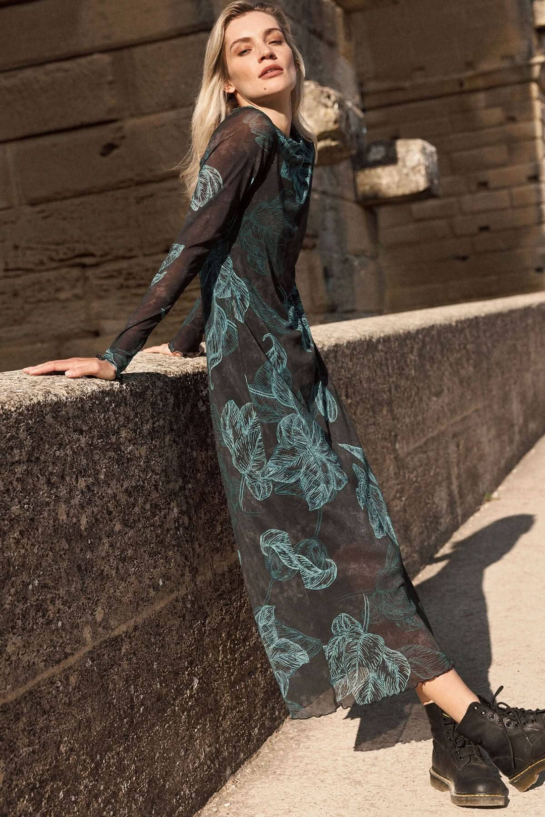 Jolie robe longue à manches transparentes avec un imprimé de feuilles, portée avec des bottes pour un look décontracté.