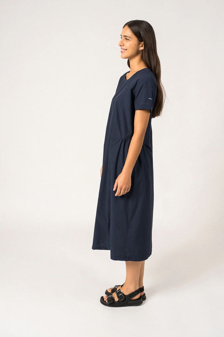 Femme portant la robe midi Morgane, coupe droite, encolure ronde, manches courtes, couleur marine, style intemporel et féminin.