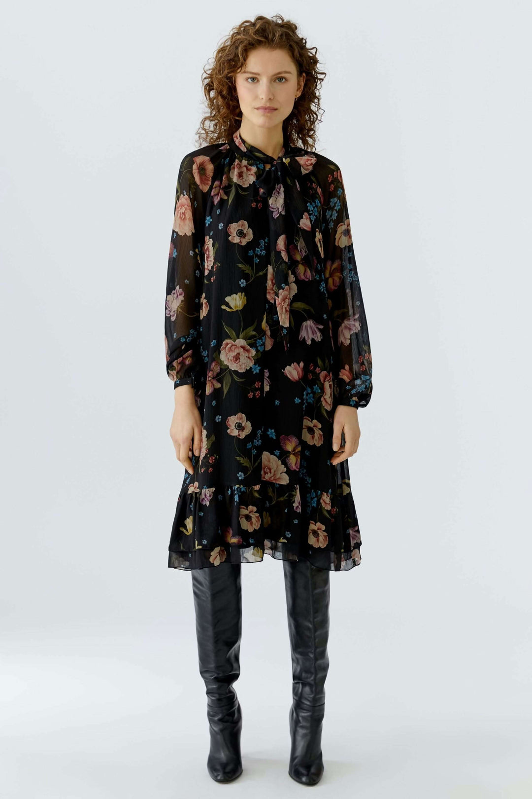 Robe midi fluide avec imprimé floral, coupe droite, encolure à lien, portée avec bottes noires. Décris moi le produit en français.