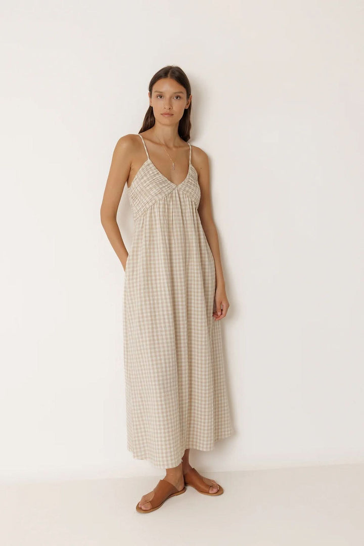 Femme portant une robe midi à motif vichy avec fines bretelles et encolure en V, idéale pour une journée ensoleillée.