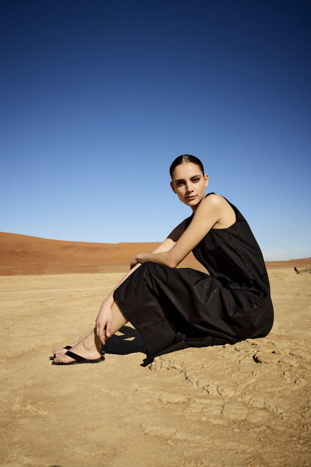Femme portant une robe midi sans manches à col chemise dans un désert sous un ciel bleu
