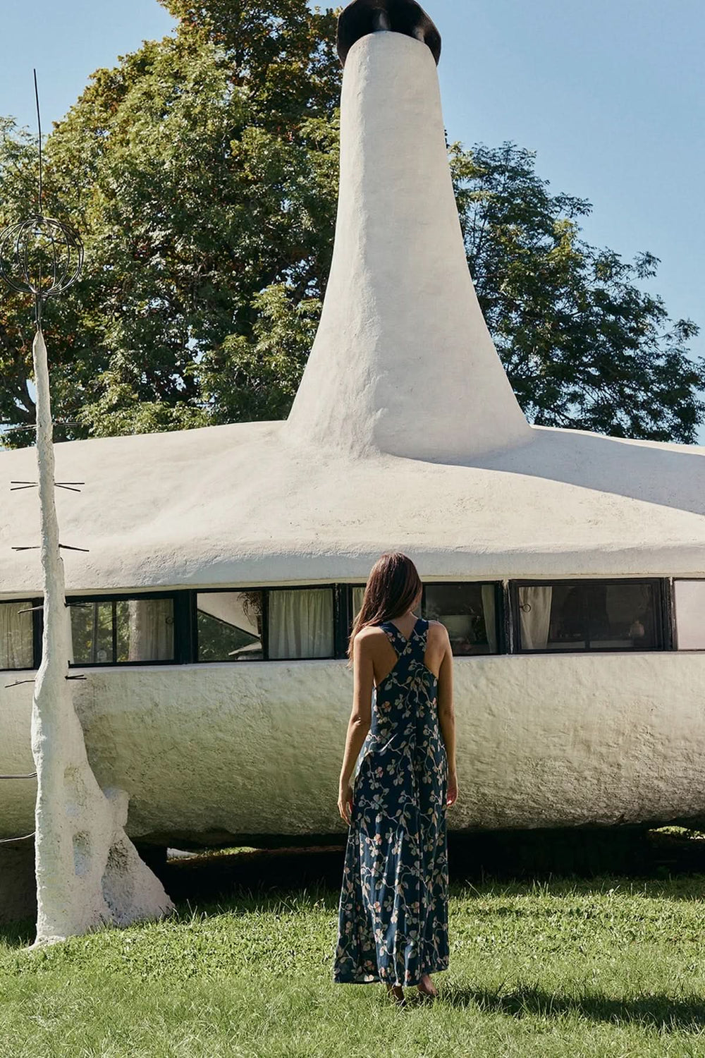 Femme portant une robe midi sans manches à imprimé floral devant une maison unique
