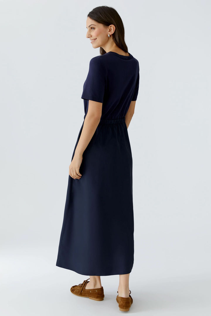 Femme portant une robe midi à taille ajustable vue de dos, avec un design minimaliste et contemporain, parfaite pour un style élégant.