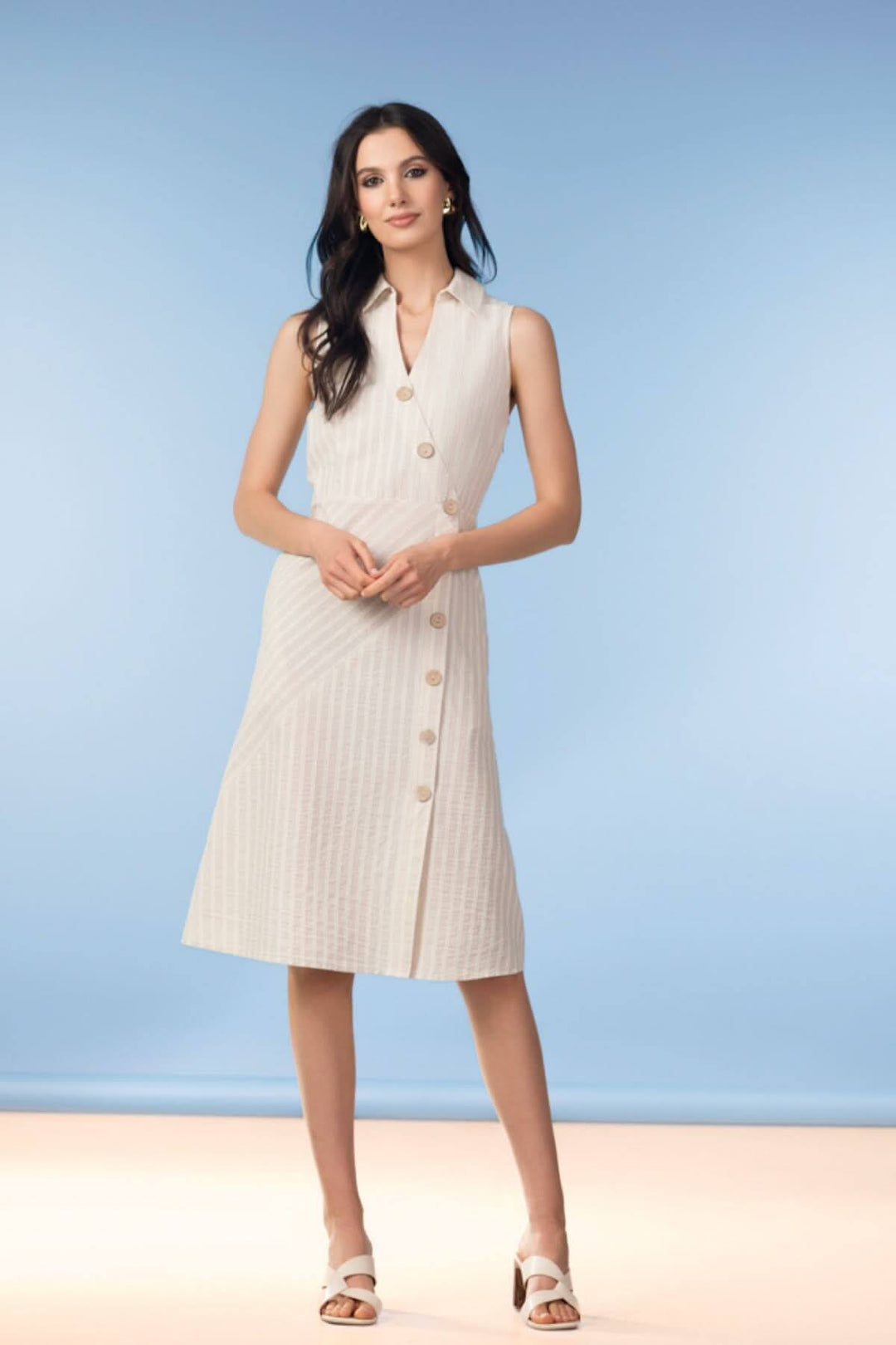 Femme portant une robe portefeuille boutonnée sans manches, coupe évasée, idéale pour un look professionnel ou habillé.