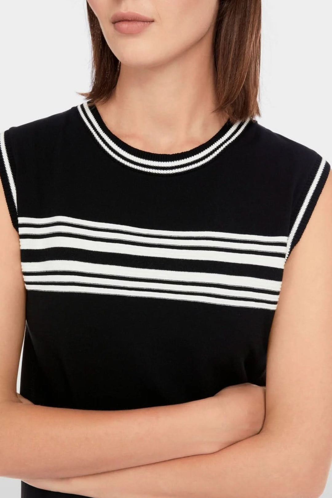 Close-up of a black sleeveless dress with striped neckline and trendy side seams.
