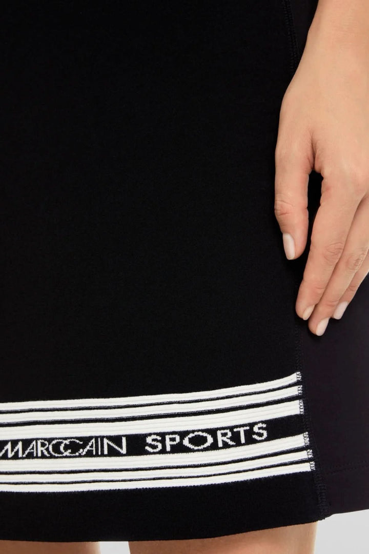 Detail shot of a black sporty dress showcasing the striped MarcCain Sports logo at the hem.