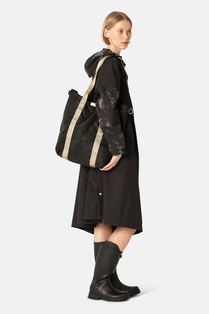 Femme portant un Sac Cabas à main en nylon avec bandoulière ajustable, fond résistant, sangles logotées, idéal pour le style et la fonctionnalité.