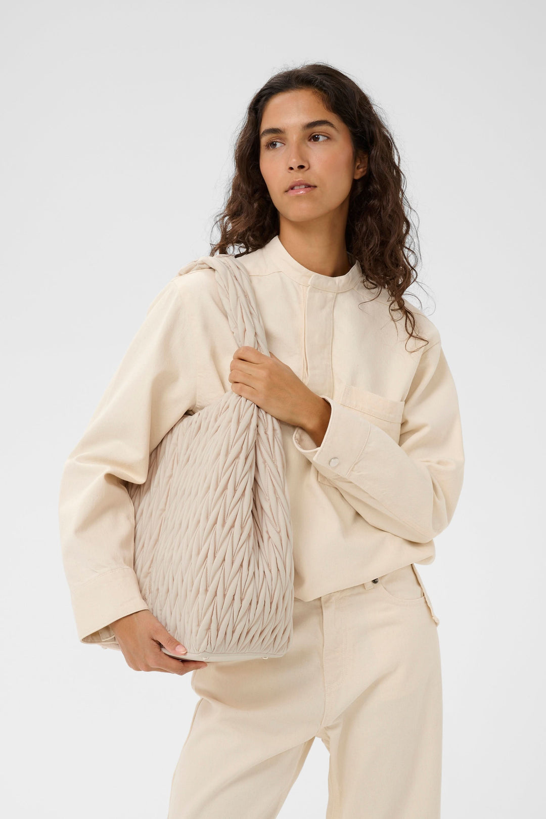 Femme portant le sac fourre-tout matelassé Samy avec texture à relief, idéal pour un look urbain et pratique.