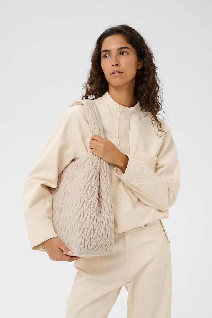 Femme portant le sac fourre-tout matelassé Samy avec texture à relief, idéal pour un look urbain et pratique.