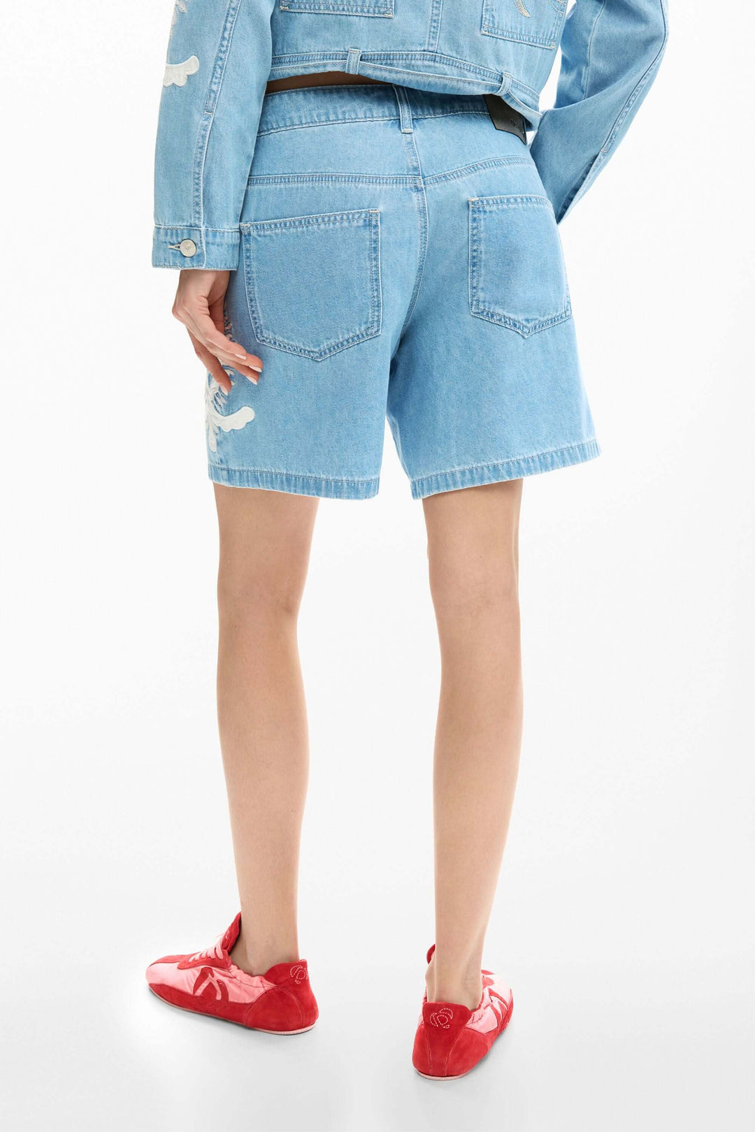 Short en jean brodée avec motifs, coupe droite, montré de dos avec poches, idéal pour un look estival confortable et stylé.