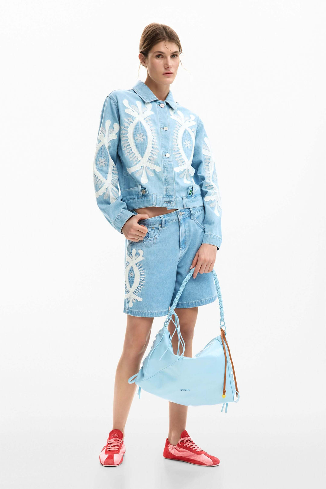 Modèle portant un short en jean brodée avec veste coordonnée, accent graphique distinctif, idéal pour un look estival polyvalent.