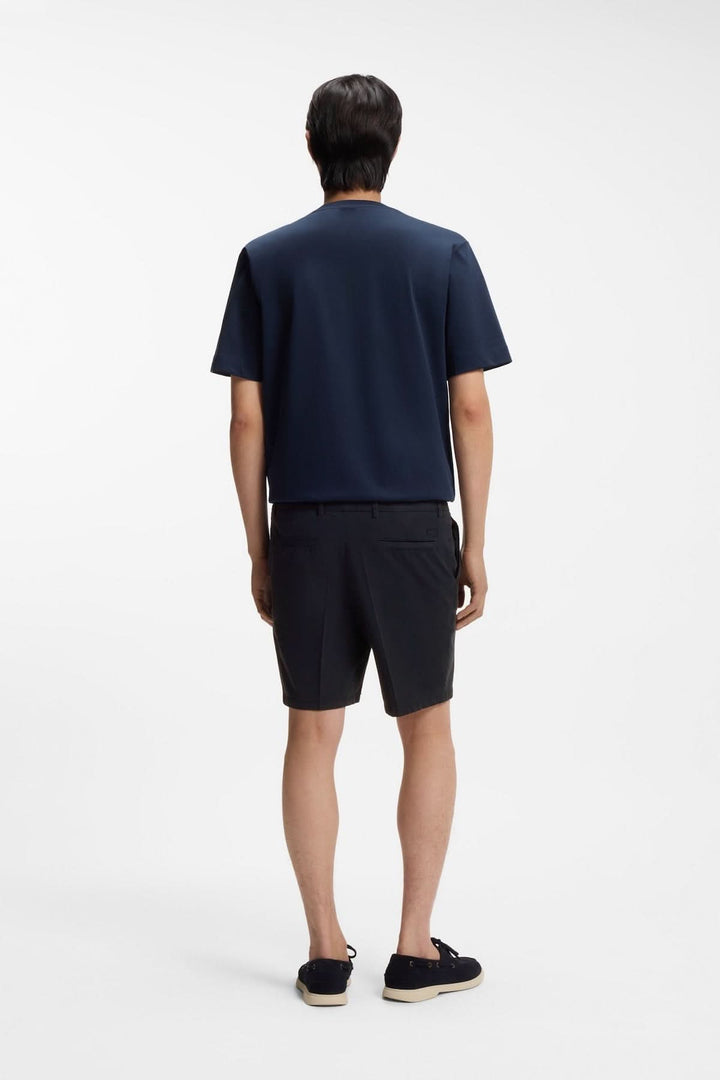 Homme portant un short structuré à coupe droite, vu de dos, avec un t-shirt bleu marine, style estival moderne et épuré.