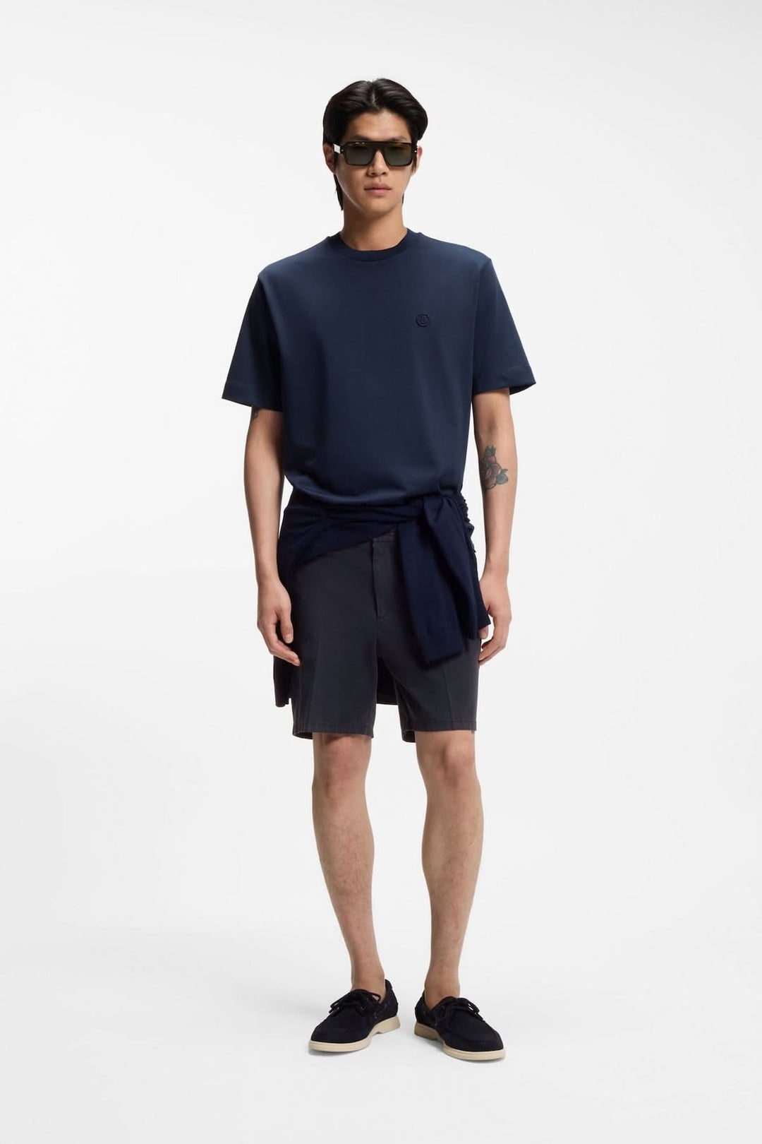 Homme portant un short structuré à coupe droite bleu marine, avec t-shirt assorti, idéal pour un look estival élégant.