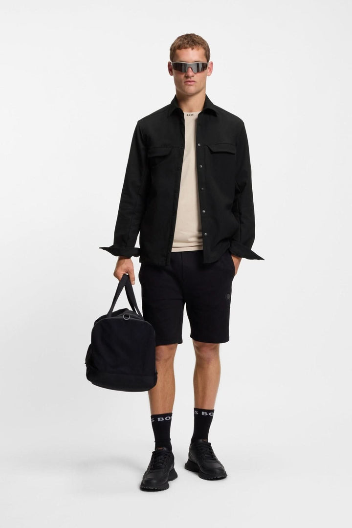 Homme portant une surchemise décontractée déperlante en gabardine BOSS, tenue moderne avec accessoires, mise en scène tendance.