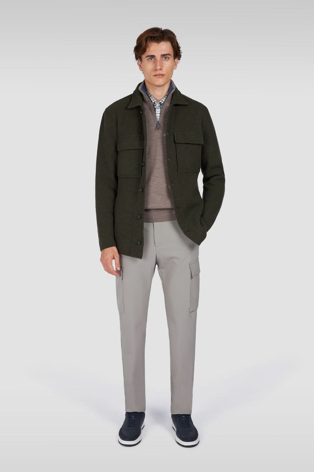 Homme portant une surchemise en laine texturée avec poches plaquées, style élégant décontracté, pantalon gris, chaussures bleu marine.