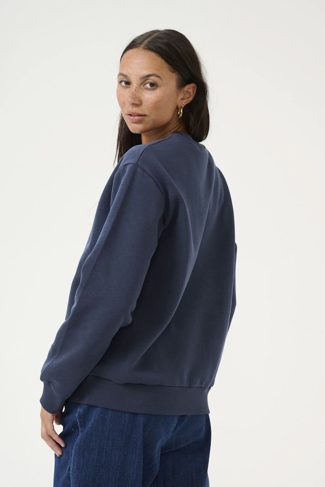 Woman wearing a navy blue casual sweat-shirt with long sleeves and a relaxed fit, styled with jeans.