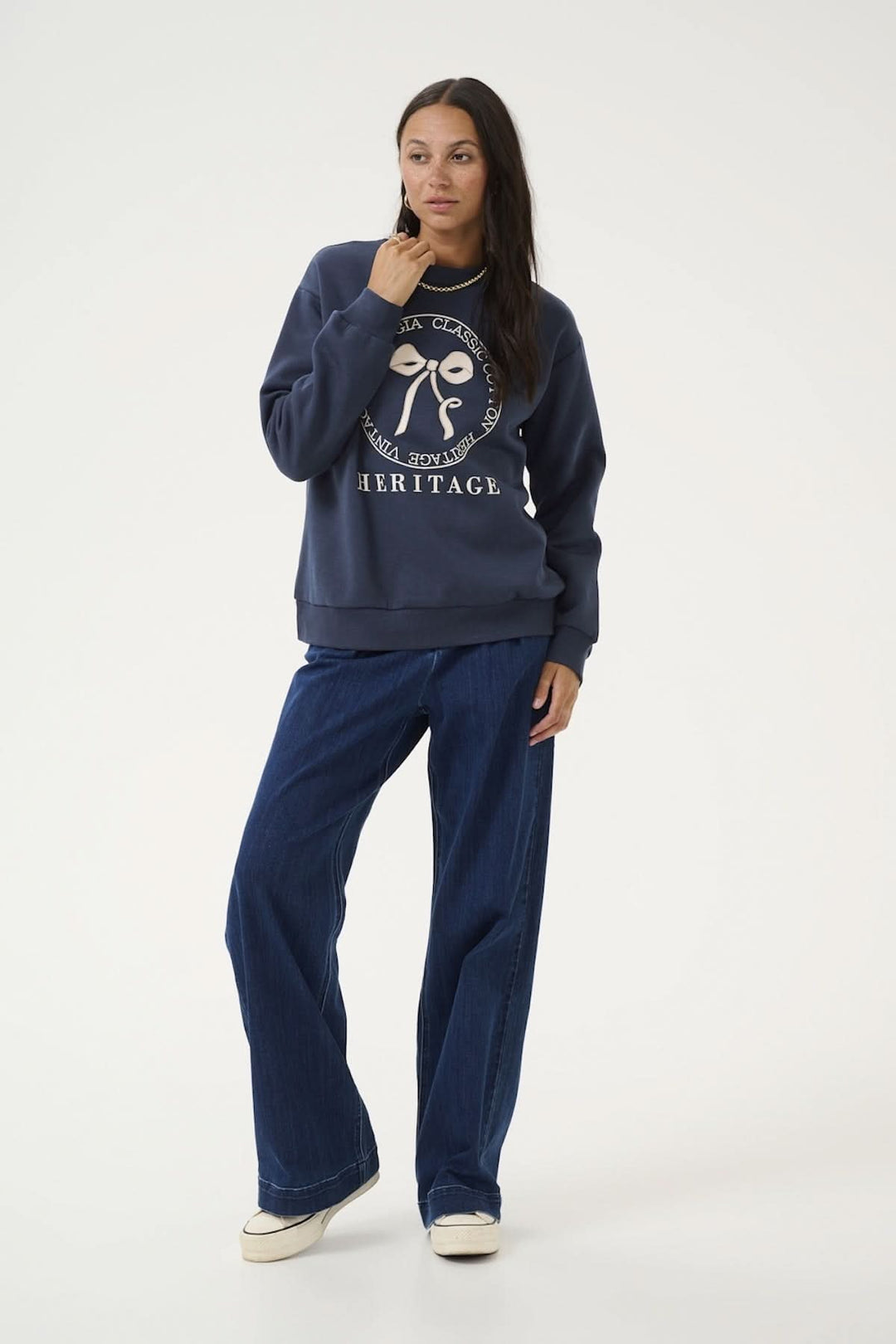 Femme portant un sweat-shirt navy confortable avec un motif central et un jean décontracté.