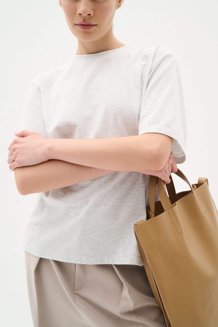 Amilla T-shirt in light gray, featuring a relaxed fit and classic round neckline, paired with a tan handbag.