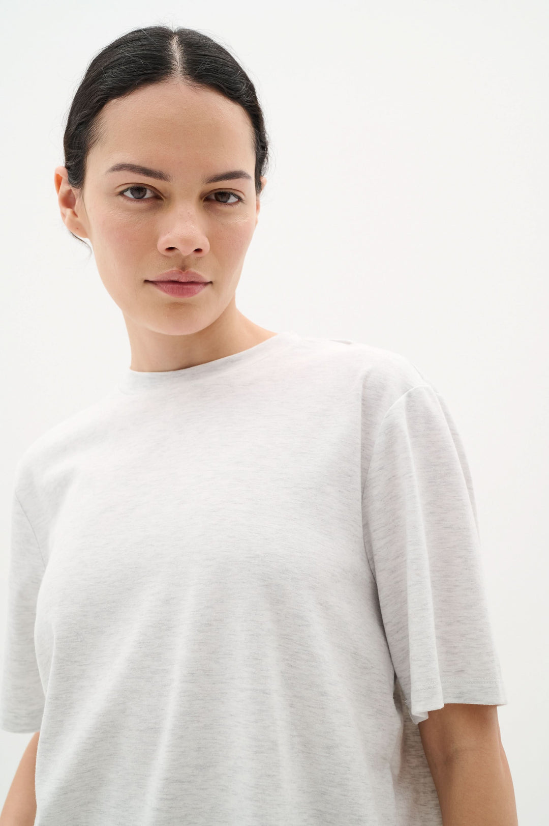 Model wearing a light gray T-shirt Amilla with a classic round neck and relaxed fit, showcasing modern comfort.