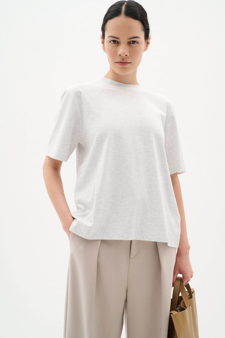 Woman wearing a light gray Amilla t-shirt with a relaxed fit and classic round neckline, styled with beige trousers.