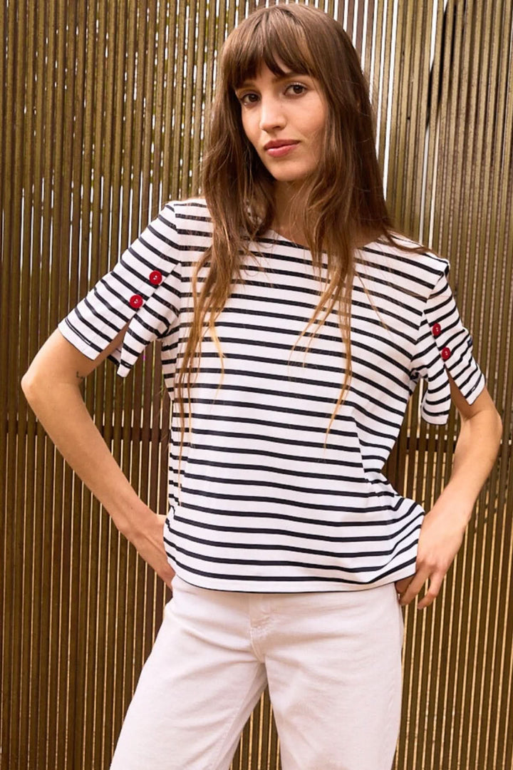 Femme portant un T-shirt CAP LEVI rayé avec manches courtes décorées de boutons, style marin moderne et féminin.