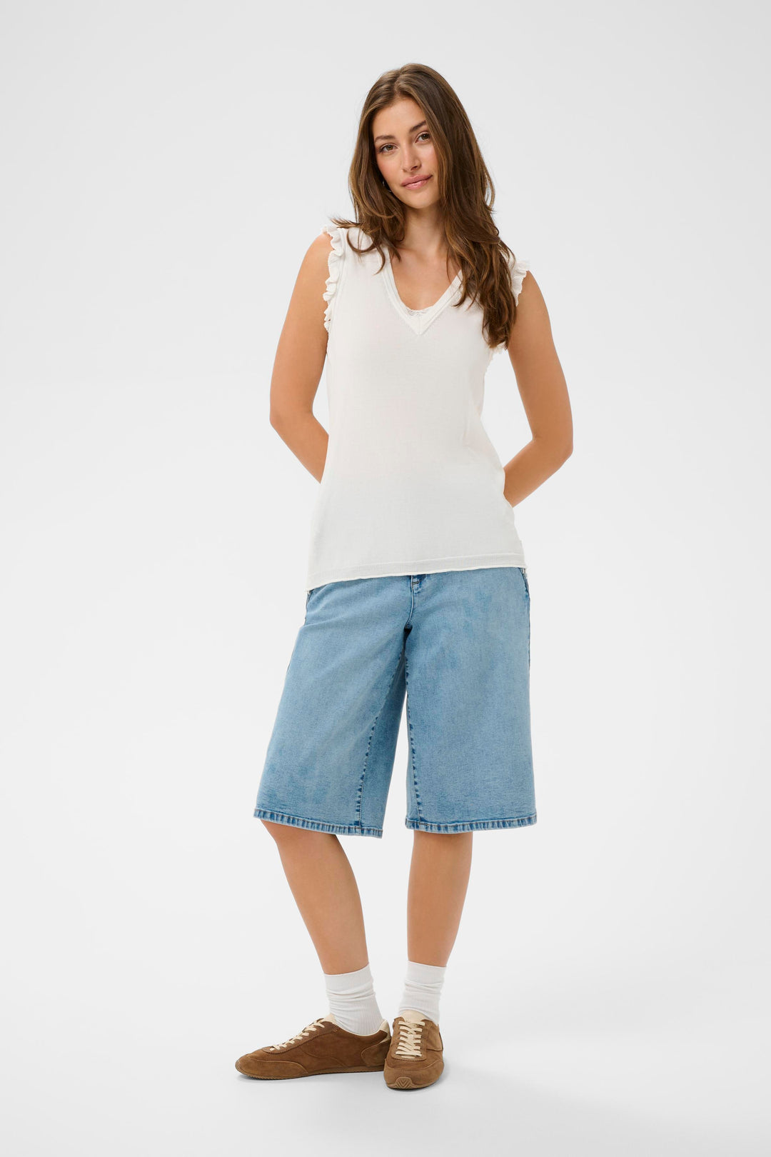 Femme portant un T-shirt Desten sans manches avec encolure en V et détails volantés, associé à un short en jean.