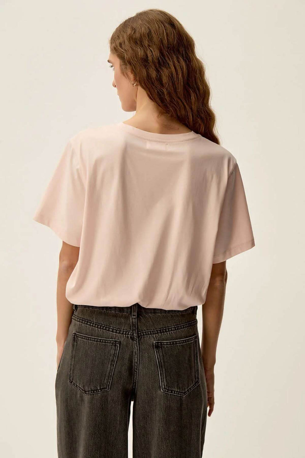 Vue arrière d'un t-shirt rose nude Gazoline en jersey doux, porté avec un jean noir.