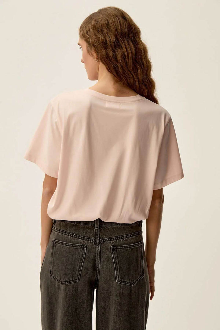 Vue arrière d'un t-shirt rose nude Gazoline en jersey doux, porté avec un jean noir.