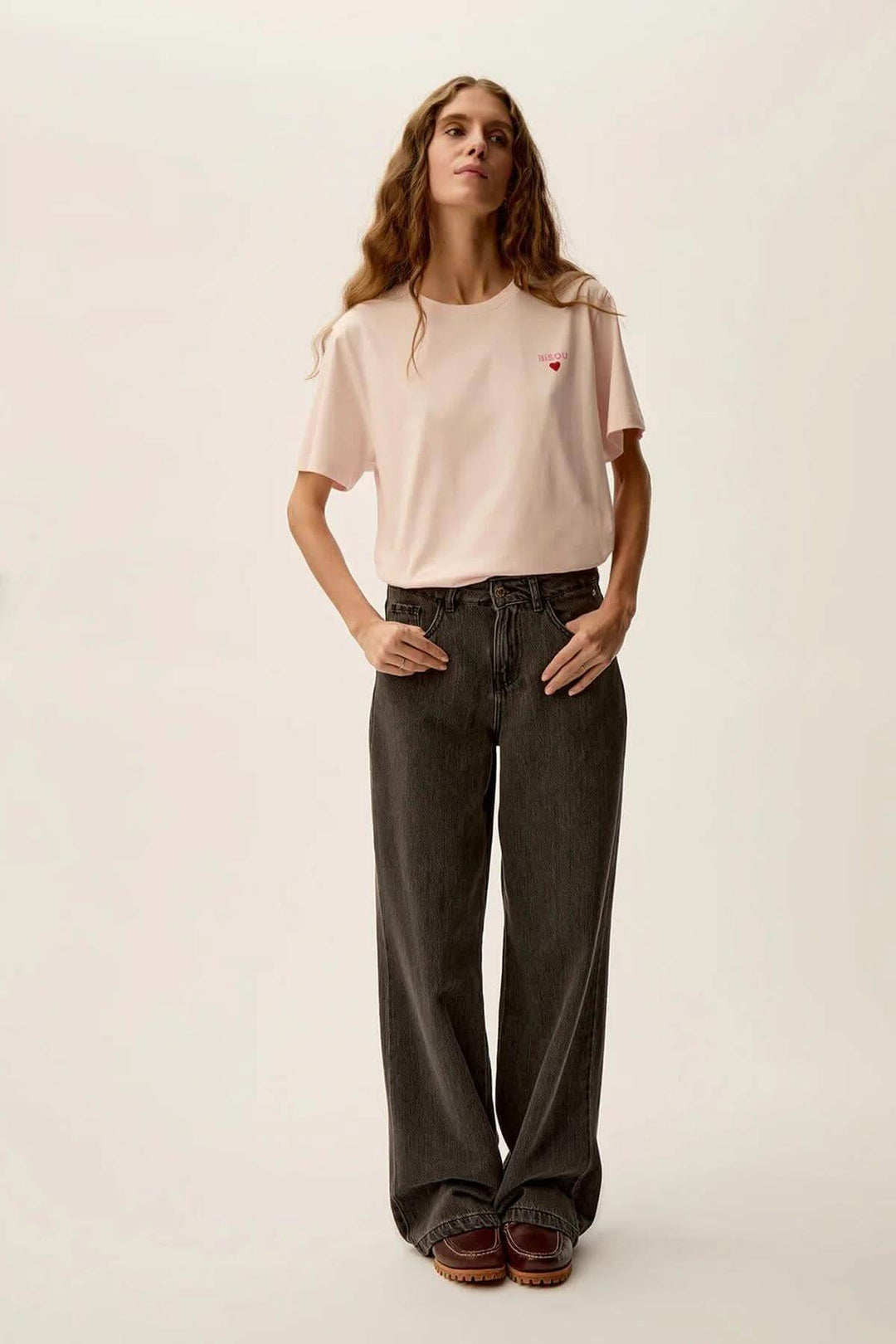 Femme portant un t-shirt rose doux Gazoline avec impression 'Bisous' et pantalon large.