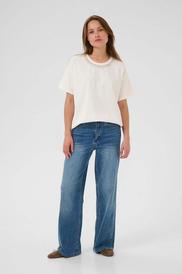 Femme portant un t-shirt Helen ajusté avec col rond et manches courtes, style minimaliste décontracté en maille extensible et douce.