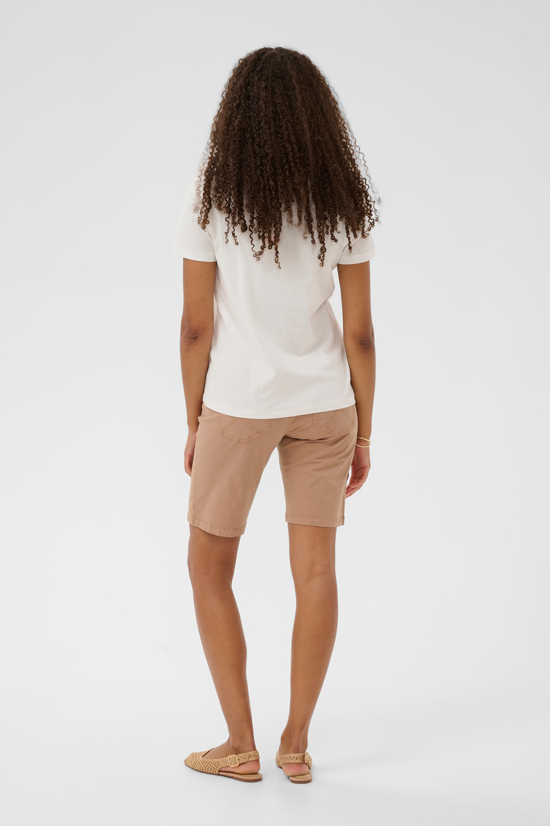 Vue arrière d'une femme portant le T-shirt Joliy avec imprimé artistique, coupe droite et manches courtes, associé à un short beige.