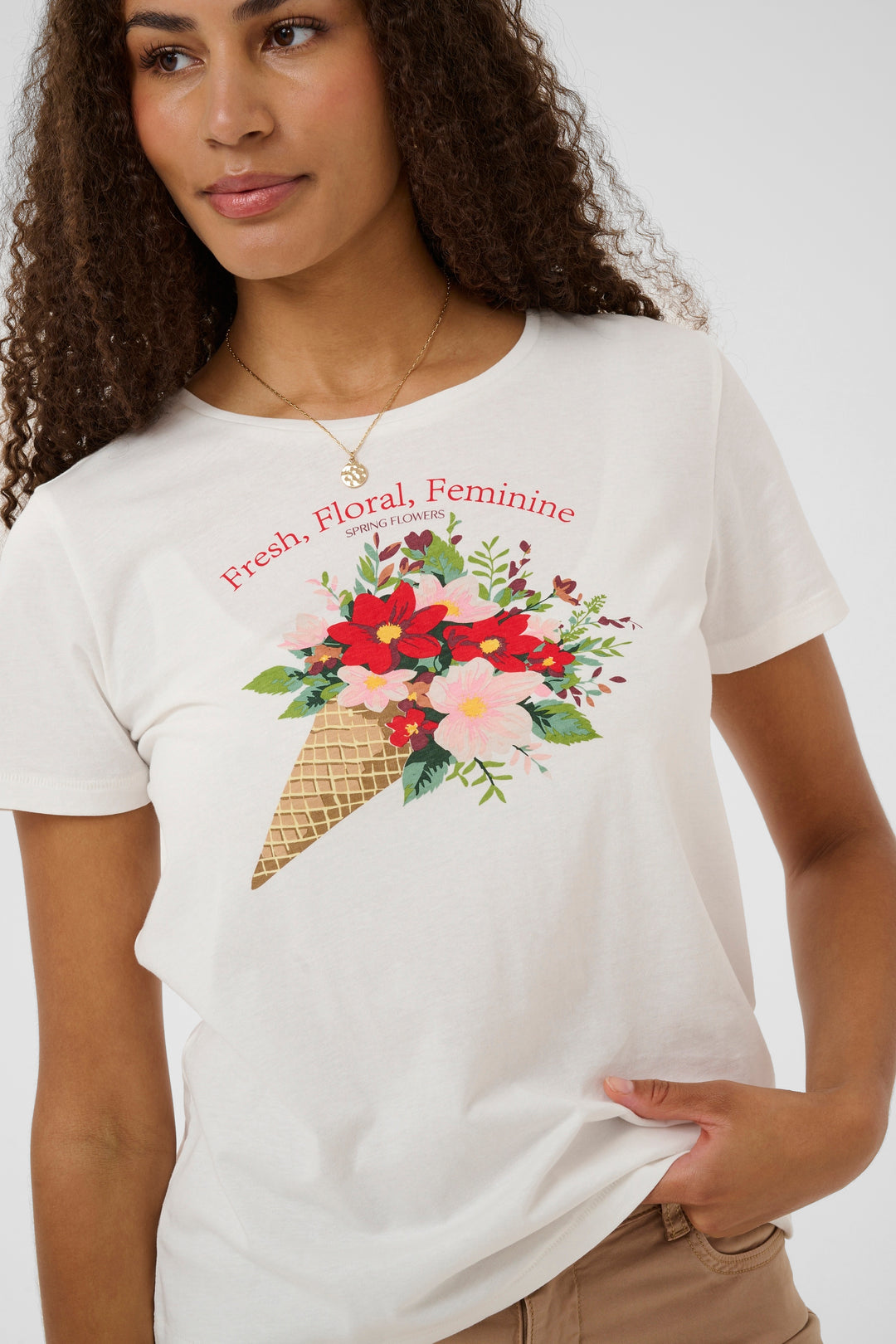 Femme portant un T-shirt Joliy avec imprimé artistique floral et texte "Fresh, Floral, Feminine", coupe droite et manches courtes.