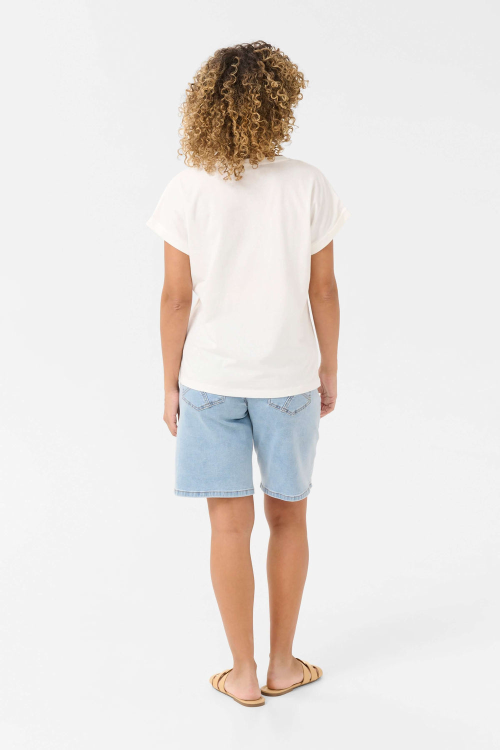 Femme vue de dos portant un t-shirt blanc en coton et un short en denim, style décontracté d'été.