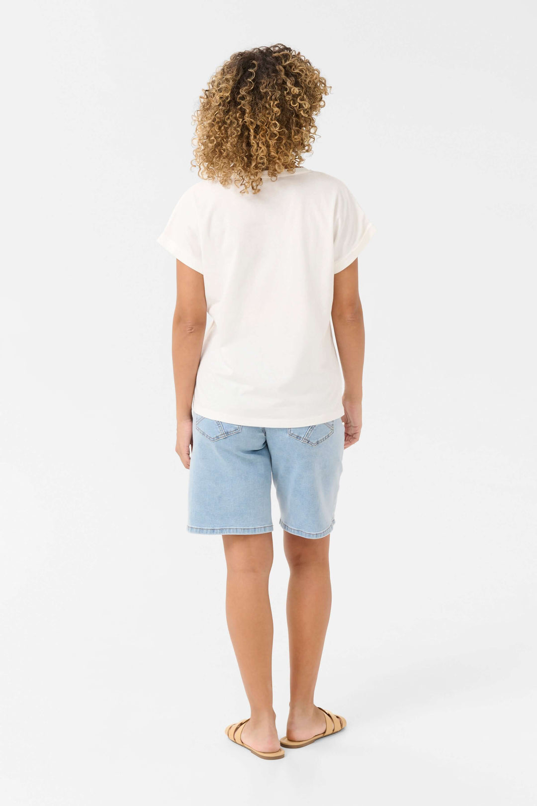 Femme vue de dos portant un t-shirt blanc en coton et un short en denim, style décontracté d'été.