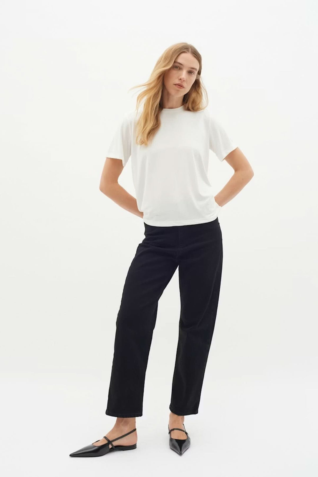 Femme portant un T-shirt Liliana blanc avec une coupe droite et encolure ronde, idéal pour un style minimaliste et polyvalent.