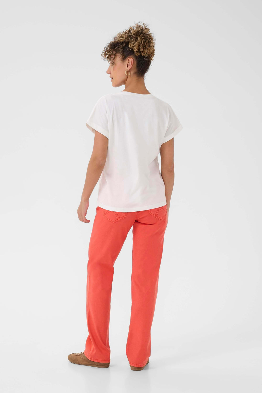 Person wearing T-shirt Lumilla in white with red pants, side view
