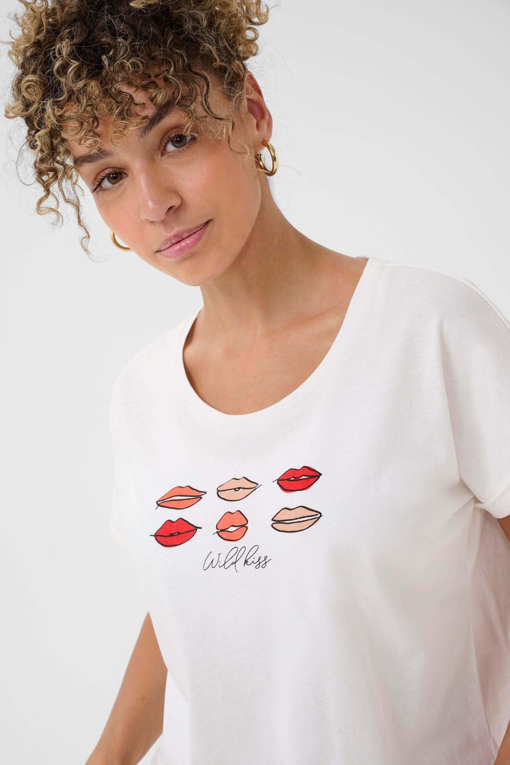 Femme portant le T-shirt Lumilla blanc avec imprimé lèvres colorées, style casual féminin, coupe confortable et encolure arrondie.