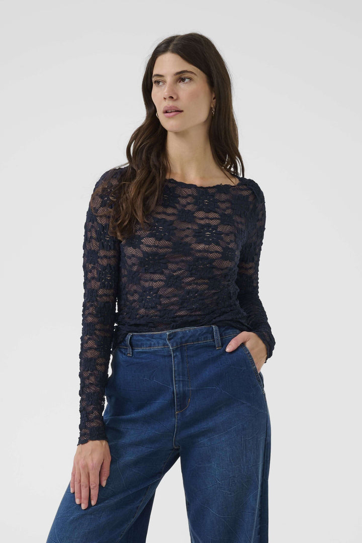 Femme portant un T-shirt Maddie en dentelle avec manches longues, coupe ajustée, élégance sophistiquée et féminine.