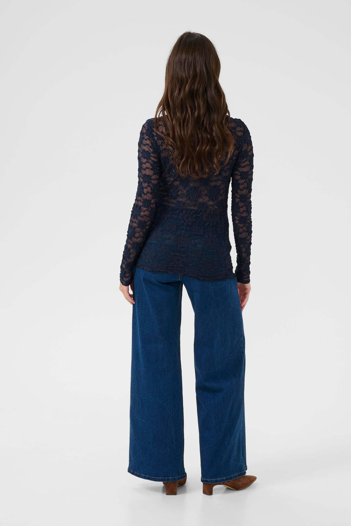 Vue arrière du T-shirt Maddie en dentelle élégante avec coupe ajustée, associé à un jean ample, idéal pour un look raffiné au quotidien.