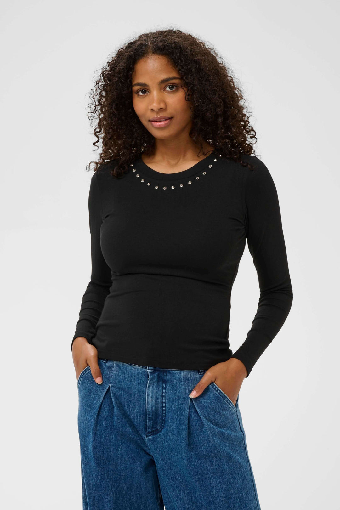 Femme portant le T-shirt Marty à manches longues ajusté avec détails décoratifs à l'encolure, idéal pour un style soigné.